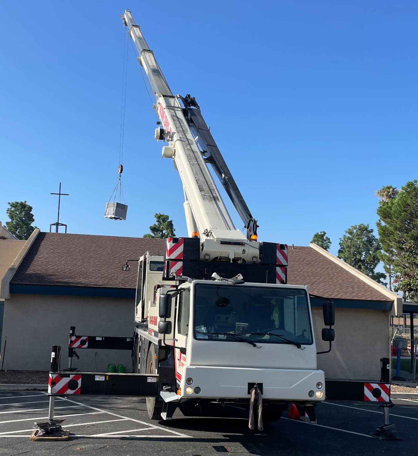 Crane setting a rooftop unit on a commercial building