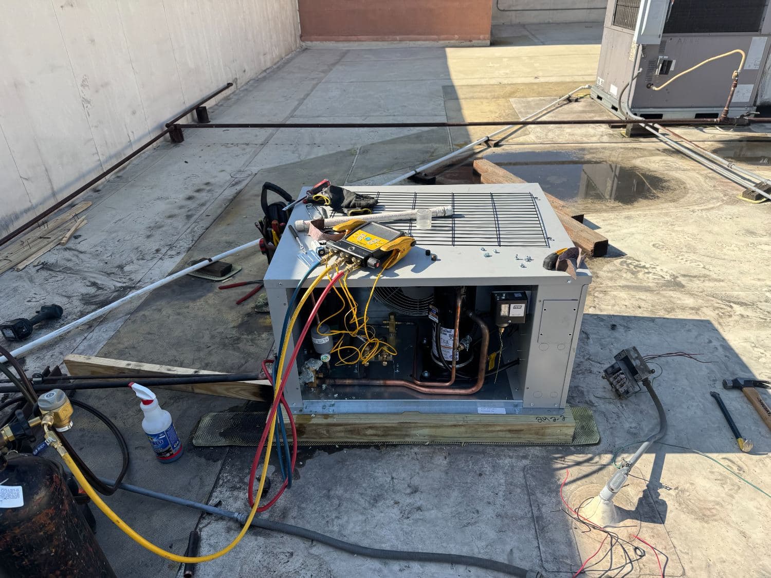 Technician charging a packaged rooftop unit with manifold gauges