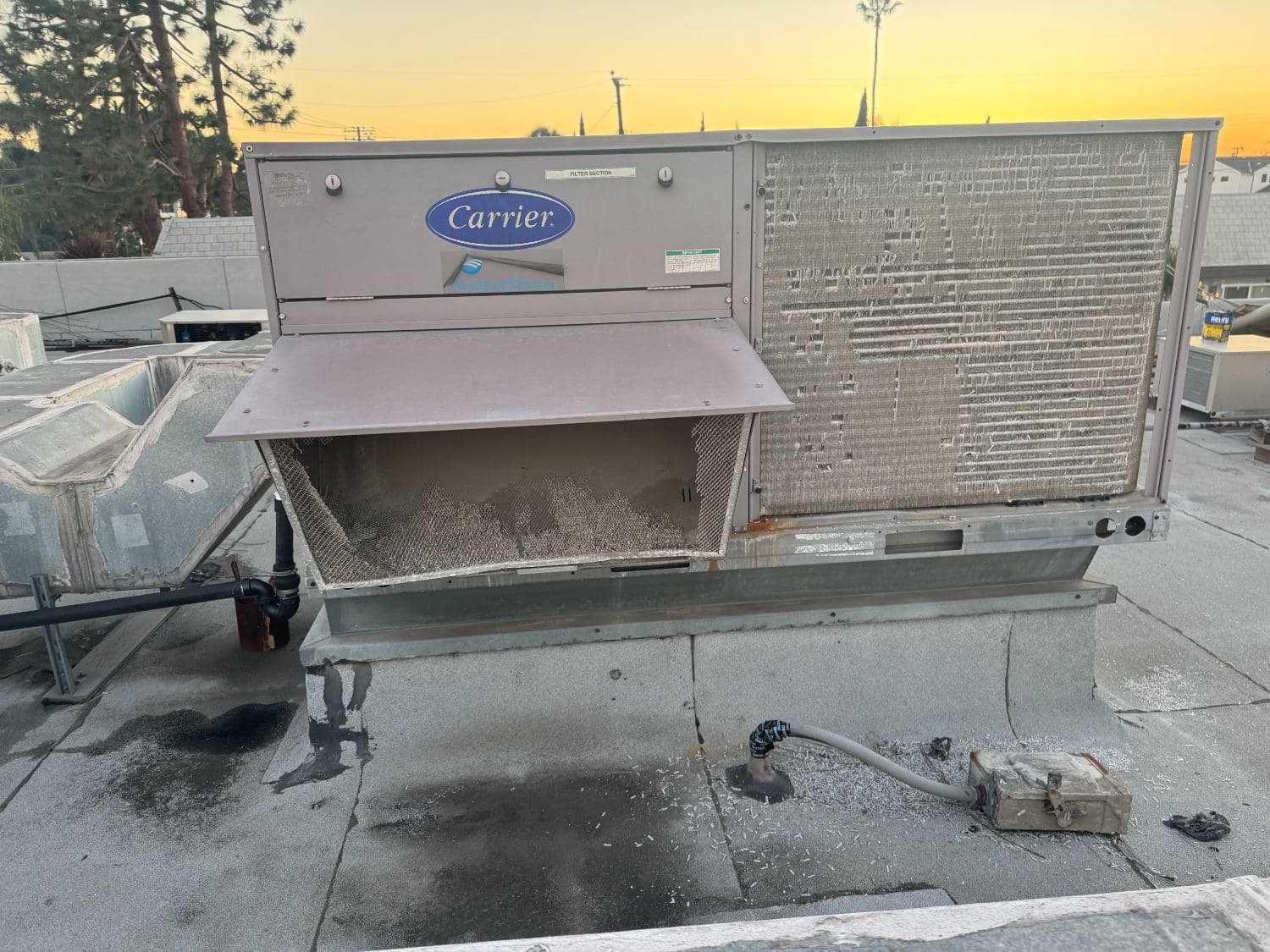 Anaheim Air servicing a packaged rooftop unit at sunset